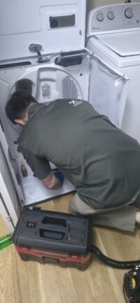 Technician reaching into a stacked dryer unit