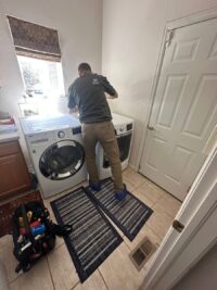Technician checking a dryer installed in a tight laundry closet