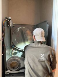 Technician working behind a dryer on the blower housing