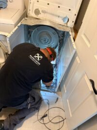Technician inspecting dryer airflow components with the panel off