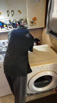 Technician diagnosing a front load dryer in a Denver kitchen