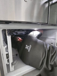 Technician inspecting a freezer compartment with a work light in Denver Metro