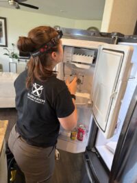 Technician checking a top freezer compartment during a service call
