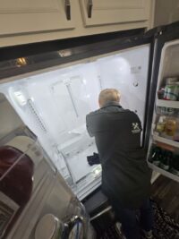 Open freezer door with a technician checking for airflow problems