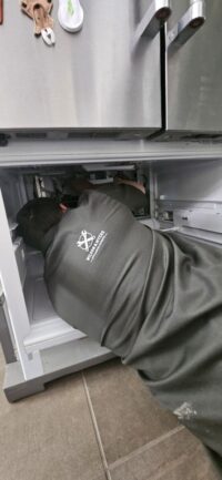Technician servicing a bottom freezer drawer in a Denver Metro home
