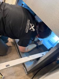 Technician inspecting a freezer drawer with a work light
