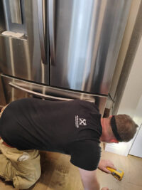 Technician checking the lower section of a freezer for noise