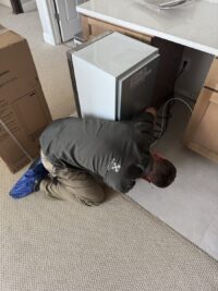 Technician working beneath a freezer on the compressor area