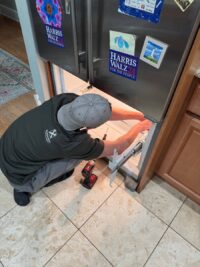 Technician checking the fan area at the bottom of a freezer