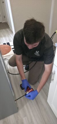 Technician in gloves inspecting the base of a freezer