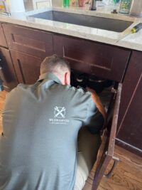 Technician working under the sink on a garbage disposal unit