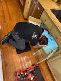 Technician reaching under the sink cabinet during a disposal repair