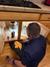 Technician servicing a garbage disposal beneath a kitchen island