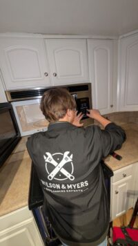 Technician servicing a built in microwave above a range in Denver Metro