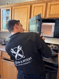 Technician working on an over the range microwave in a Denver kitchen