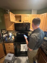 Technician removing a built in microwave panel to reach the components