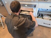 Technician servicing a built in oven in a Denver Metro kitchen