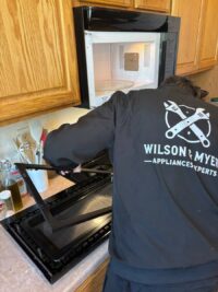 Technician handling an oven door during a glass repair