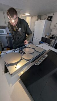 Technician checking burner caps and grates removed from a gas range