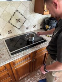 Technician testing a cooktop surface after a repair