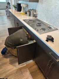 Technician reaching under a cooktop to check the burner wiring