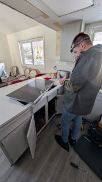 Technician lifting a cooktop to reach the components beneath