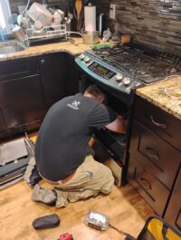 Technician working under a cooktop in a Denver kitchen