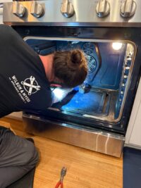 Technician inspecting an oven cavity with a work light