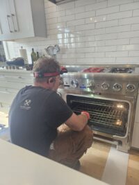 Technician checking oven heating components with the door open