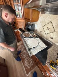 Technician servicing a glass cooktop with the surface lifted