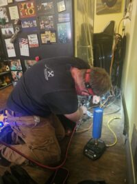 Technician brazing a sealed system line during refrigerator repair in Denver Metro