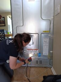 Technician removing the lower grille to clean refrigerator condenser coils