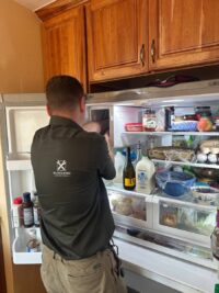 Technician checking fresh food compartment airflow in a stocked refrigerator