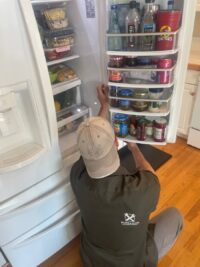 Technician checking a fully stocked refrigerator during a Denver service call