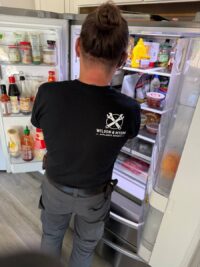 Technician checking cooling performance inside a stocked refrigerator