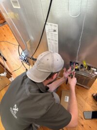 Technician testing a refrigerator control board with the panel opened