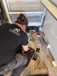 Technician tracing refrigerator wiring during an electrical diagnosis