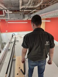 Technician tracing refrigerant lines at a walk-in unit in Denver Metro