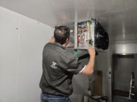Technician at the control panel inside a walk-in unit