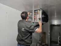 Technician checking walk-in controls during a temperature call