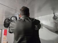 Technician servicing the evaporator fans inside a walk-in