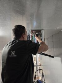 Technician inspecting the evaporator section of a walk-in
