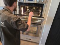 Technician servicing a stainless double wall oven in Denver Metro
