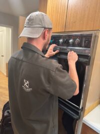 Technician checking wall oven controls during a repair