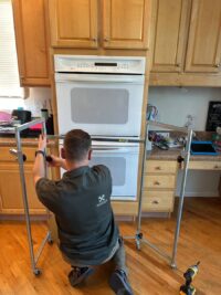 Technician working on a built in wall oven with tools at hand