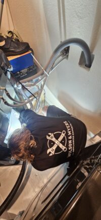 Technician clearing a washer drain line with a wet vacuum during a Denver Metro service call