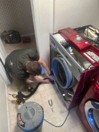 Technician pumping standing water out of a front load washer