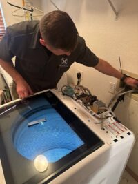 Technician checking a top load washer tub that failed to drain