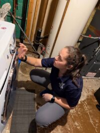 Technician checking the water supply valves behind a washer