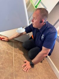 Technician inspecting the floor beside a washer for water damage